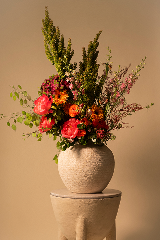 Composition florale de saison dans un vase en pierre sur socle de plâtre