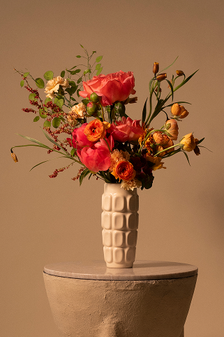 Composition florale dans un vase en céramique blanc sur socle de plâtre